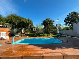 Vista externa de uma piscina e jardim em uma propriedade.