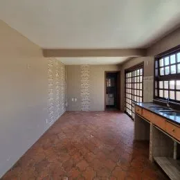 Foto de um corredor interno com piso de ladrilho avermelhado.