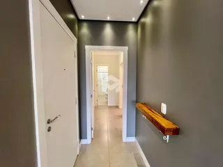 Hall de entrada com porta branca e prateleira de madeira na parede