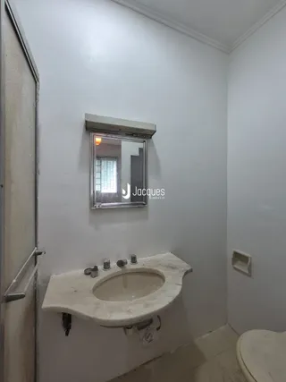 Vista de um banheiro com pia de apoio e espelho branco.
