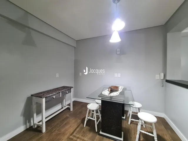 Ambiente interno de uma sala com piso de madeira e mesa de jantar.