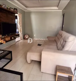 Sala de estar com sofá claro e piso de porcelanato em um imóvel no Brasil.