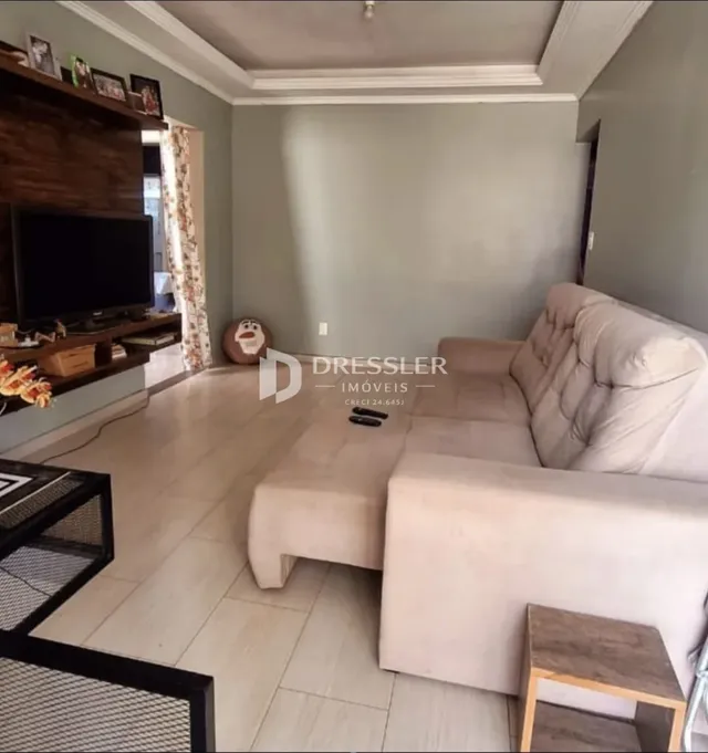 Sala de estar com sofá claro e piso de porcelanato em um imóvel no Brasil.