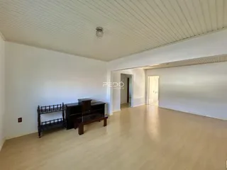 Ambiente interno de uma sala de estar com piso claro e paredes brancas.