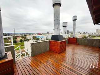 Deck de madeira com pilares de concreto em uma área externa.