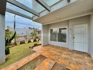 Vista externa de uma propriedade com jardim e piso de cerâmica.