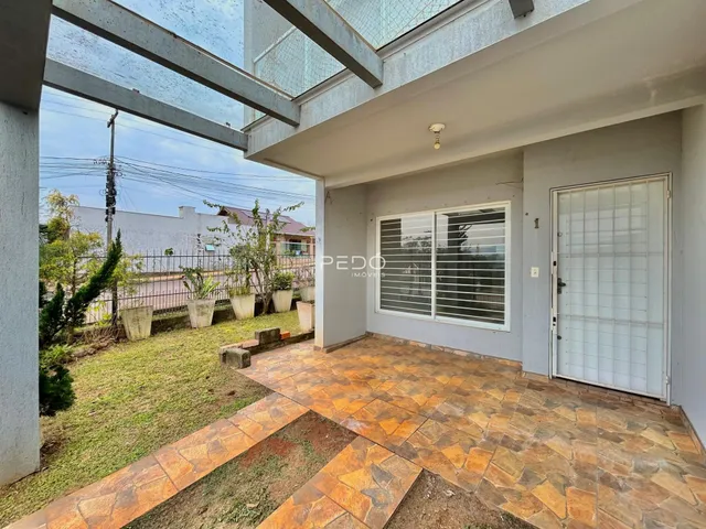 Vista externa de uma propriedade com jardim e piso de cerâmica.