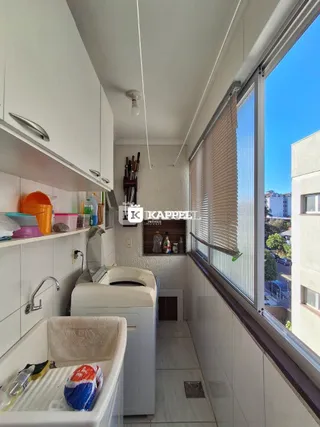 Vista interna de uma área de serviço com bancadas brancas e piso de cerâmica.