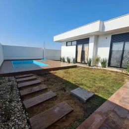 Jardim externo com gramado e caminho de pedra na propriedade.