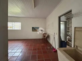 Interior de uma sala com piso de tijolos vermelhos e paredes brancas.