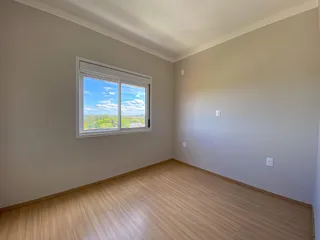 Sala de estar com piso de madeira e janela com vista para a paisagem externa.
