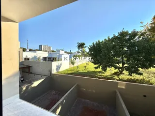 Vista externa mostrando um jardim e edifícios ao fundo.