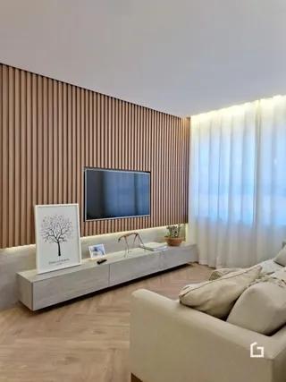 Sala de estar moderna com painel de madeira e televisão.