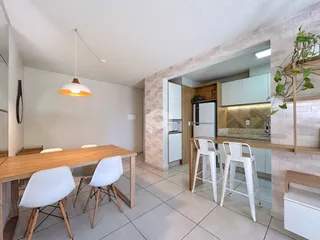 Uma sala de jantar com mesa de madeira e cadeiras brancas.