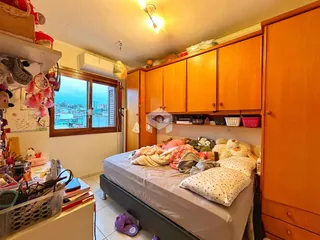 Quarto com armário de madeira e vista da cidade pela janela.