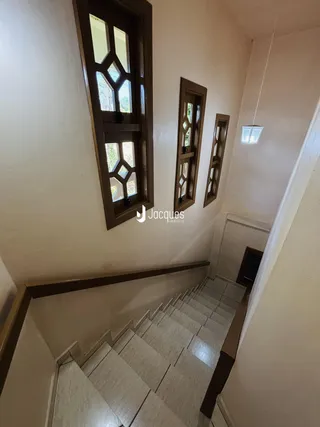 Hall com escadaria e janelas em um imóvel no Brasil.