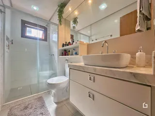 Banheiro moderno com box de vidro e bancada de mármore.
