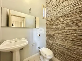 Foto de um banheiro com pia e vaso sanitário em uma parede texturizada.