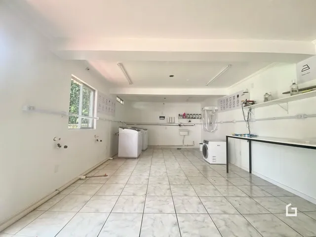 Interior de uma sala com piso de cerâmica e eletrodomésticos visíveis.