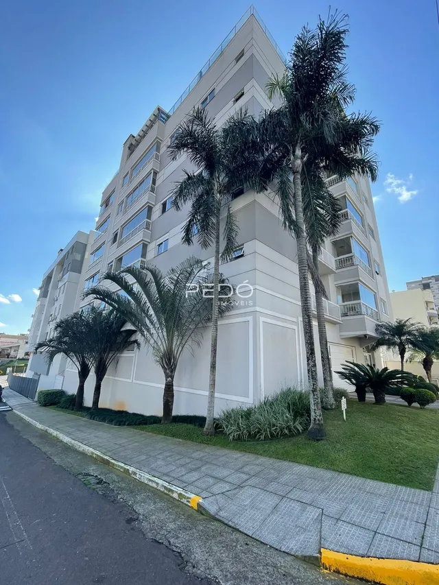 Fachada de um prédio residencial em Lajeado, Brasil, com palmeiras e gramado na frente.