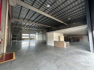 Espaço interno amplo com teto de estrutura metálica e piso de concreto.
