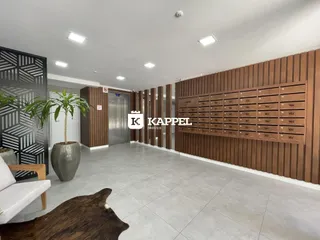 Interior de uma sala ampla com piso claro e painéis de madeira na parede.