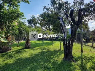 Vista externa mostrando um gramado verde e árvores no terreno.