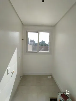 Vista de um corredor interno com paredes brancas e piso claro.