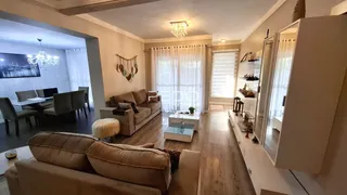 Sala de estar com piso de madeira e sofá de cor bege.