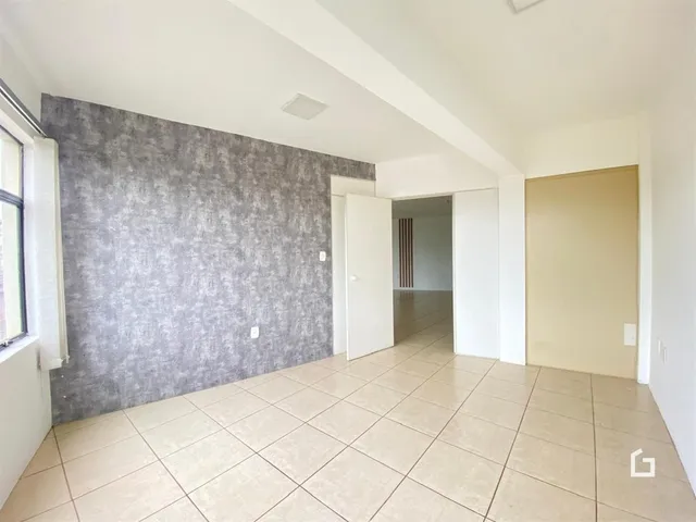 Vista interna de um ambiente com piso de cerâmica e parede texturizada.