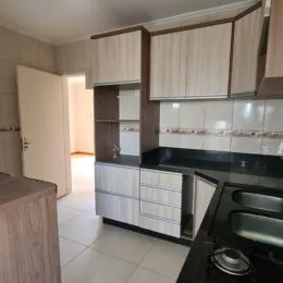 Foto interna de uma cozinha com armários superiores e bancada escura.