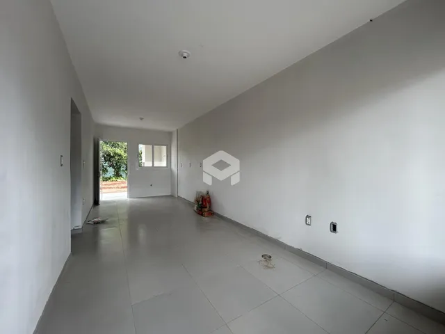 Corredor interno de uma residência com paredes brancas e piso claro.
