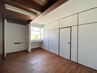 Sala de estar com piso de madeira e painéis brancos na residência.