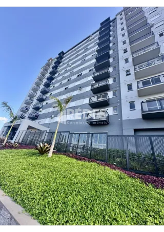 Fachada de um edifício residencial em Lajeado, Brasil, com paisagismo verde na frente.
