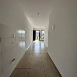 Corredor interno com paredes brancas e piso claro.