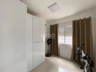Quarto com armários brancos e janela com cortinas bege.