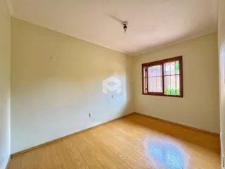 Ambiente interno de uma sala com piso de madeira clara e parede branca.