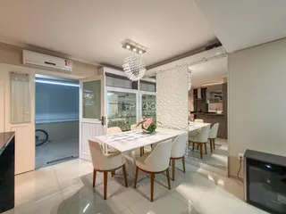 Sala de jantar iluminada com mesa branca e cadeiras em um imóvel em Lajeado.