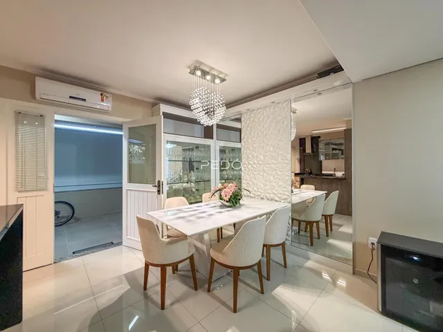 Sala de jantar iluminada com mesa branca e cadeiras em um imóvel em Lajeado.
