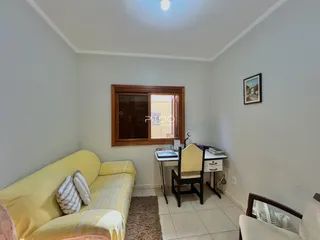 Sala de estar com sofá amarelo e janela de madeira em um imóvel no Brasil.