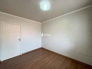 Vista interna de um cômodo com paredes brancas e piso de madeira.