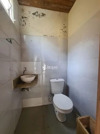 Foto interna de um banheiro com azulejos brancos e vaso sanitário.