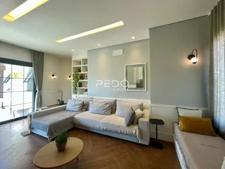 Sala de estar moderna com piso de madeira clara e grandes janelas.