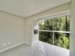 Interior de um cômodo com grande janela de vista para a vegetação.