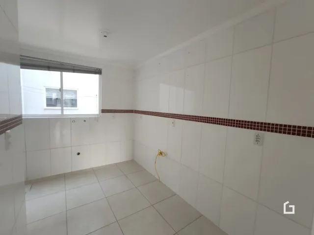 Vista interna de um corredor com paredes brancas e piso de cerâmica.