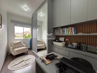 Sala de estar com um sofá claro e estantes de livros em um ambiente moderno.