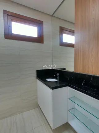Banheiro com bancada escura e revestimento de azulejos claros.