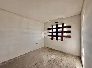 Interior de um cômodo com paredes brancas e piso de concreto aparente.