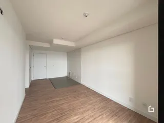 Um corredor interno com piso de madeira clara e paredes brancas.