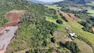 Vista aérea de uma paisagem rural com vegetação densa e campos abertos.